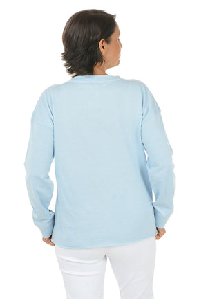 Woman wearing a light blue sweater and white pants on a white background