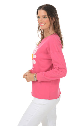 Woman wearing a pink long-sleeve sweater with a white daisy design on a white background. Side shot.