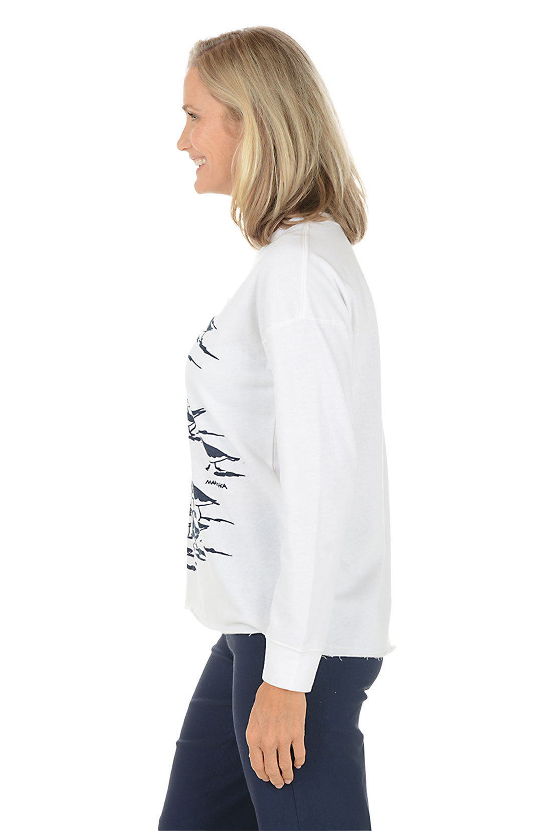 Woman wearing a white sweatshirt with black bird illustrations on a white background. Side shot.
