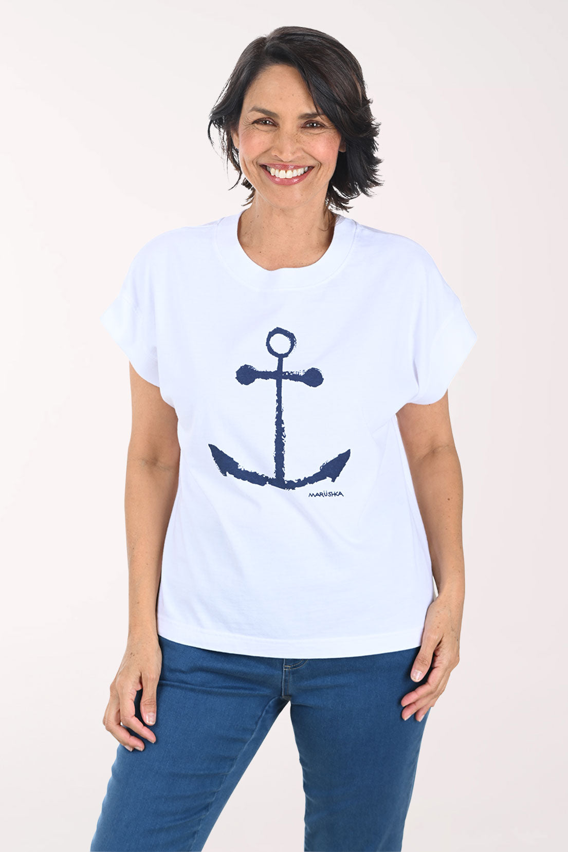 Woman wearing a white t-shirt with a blue anchor design on a plain background