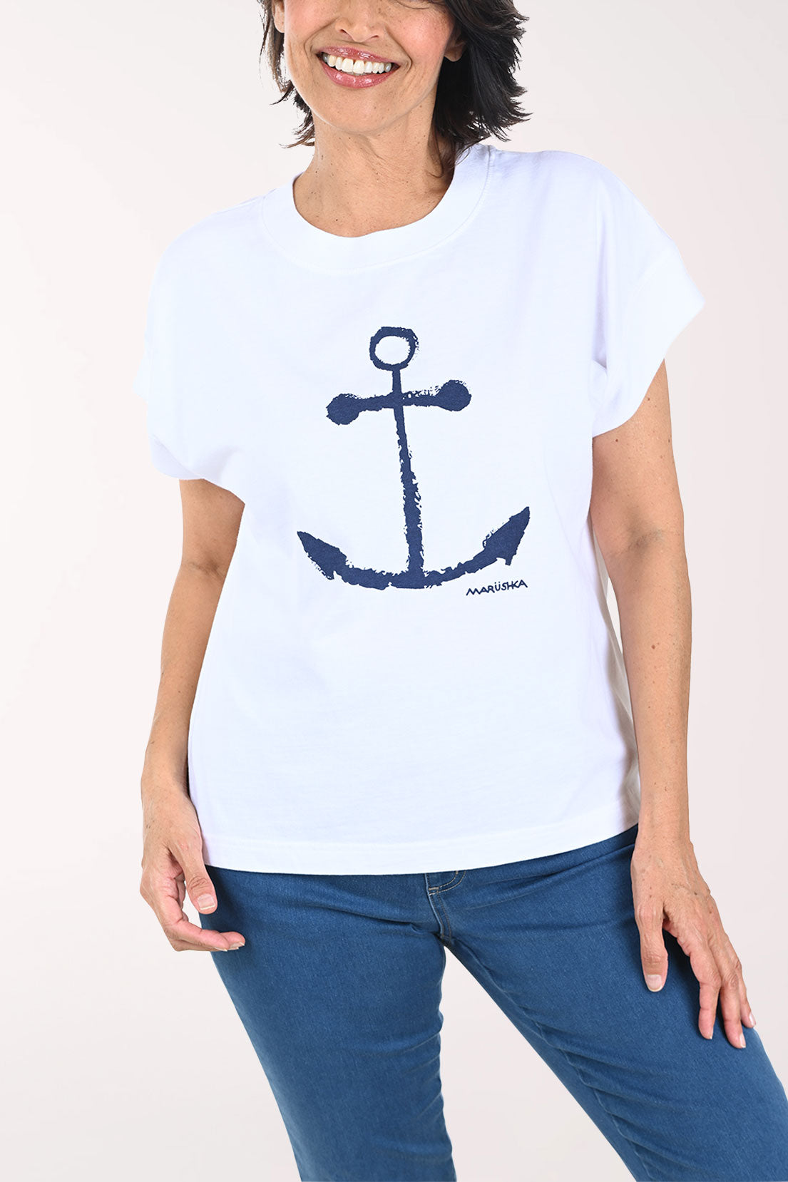 Woman wearing a white t-shirt with a blue anchor design on a plain background
