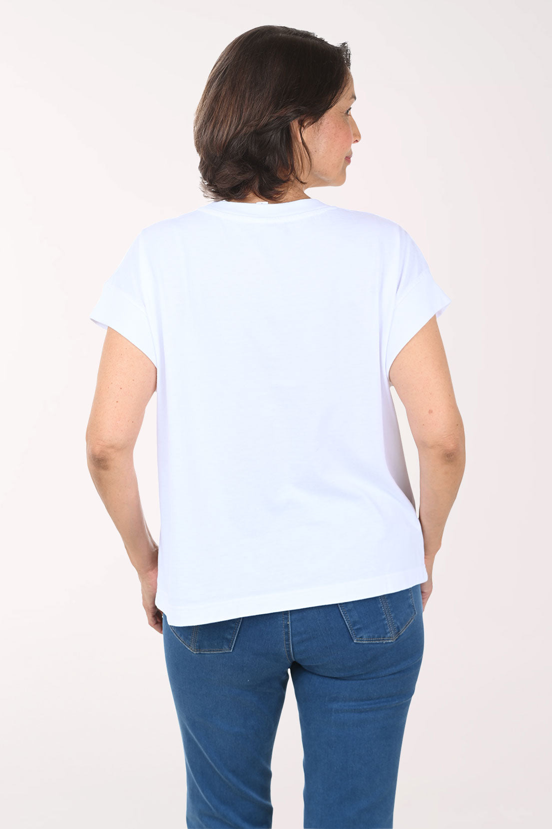 Woman wearing a white t-shirt with a blue anchor design on a plain background