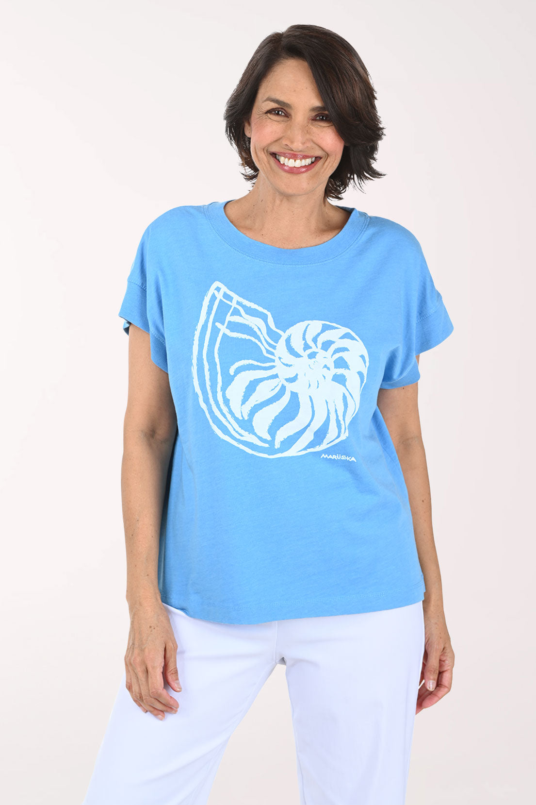 Woman wearing a light blue t-shirt with a white graphic design on a plain background