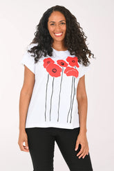 Woman wearing a white t-shirt with red floral designs on a plain background