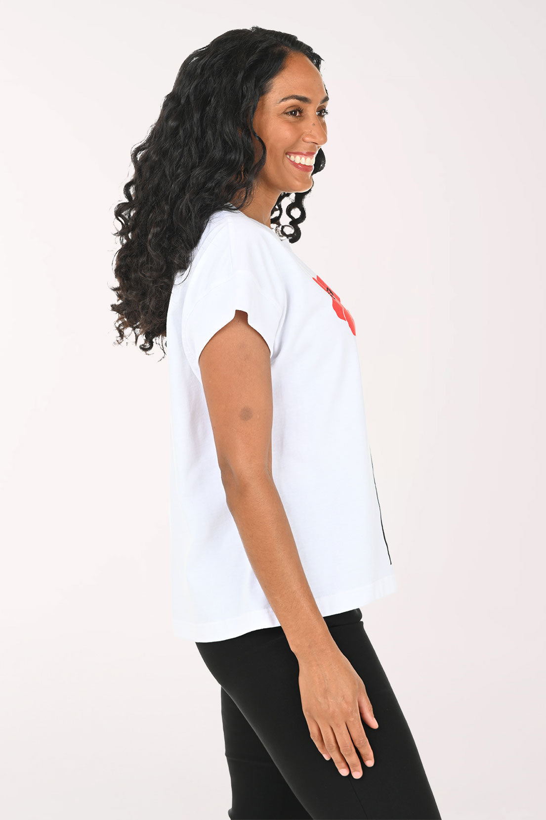 Woman wearing a white t-shirt with red floral designs on a plain background