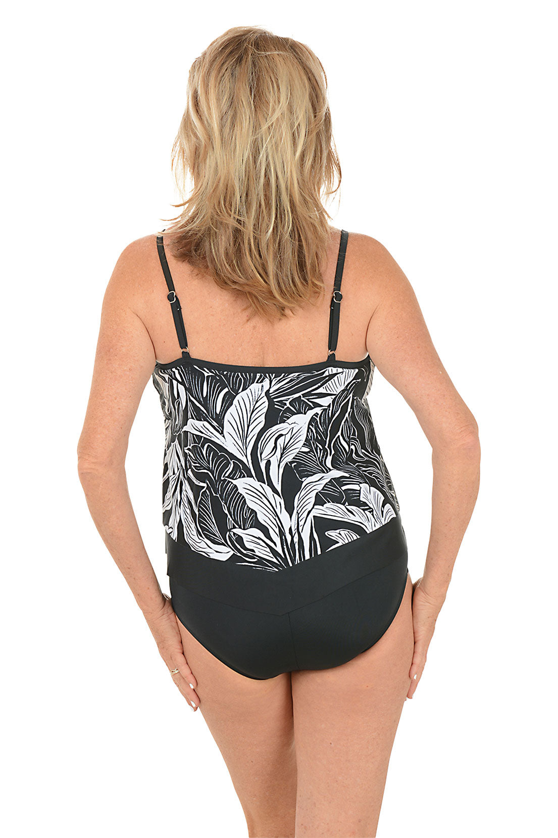 Woman wearing a black and white leaf-patterned swimsuit on a white background. Back shot.