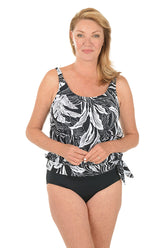 Woman wearing a black and white patterned tankini top with black bottoms on a white background.