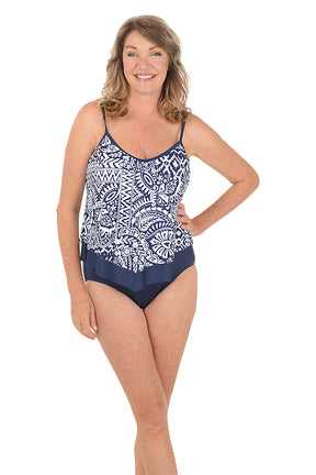 A woman wearing a blue and white one piece swimsuit with a flutter hem. Second full length shot.