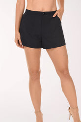 Front view of the Maxine Woven Pocketed Boardshort in black, with a zip fly, snap closure and front pockets, worn with nude strappy heeled sandals.