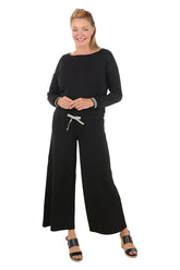 Woman wearing a black outfit with wide-leg pants on a white background