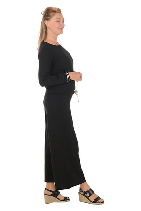 Woman wearing a black lounge set with white trim on a white background. Side shot.