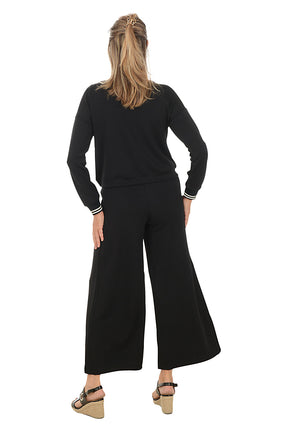 Woman wearing a black lounge set with white trim on a white background. Back shot.