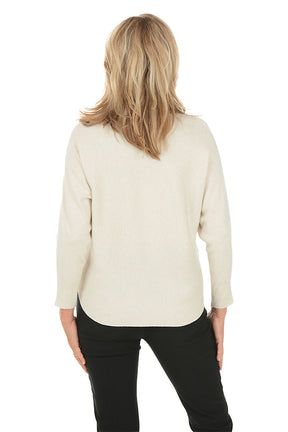 Woman wearing a cream sweater with black floral designs on a white background. Back shot.