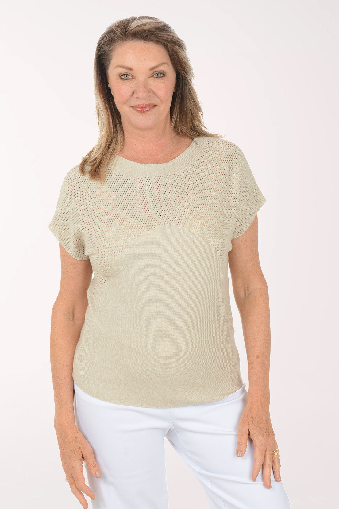 Woman wearing a beige short-sleeve top and white pants on a white background