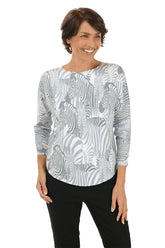 Woman wearing a grey and white zebra illustrated patterned long-sleeve top on a white background. 