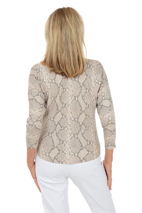 Woman wearing a snake print top and white pants on a white background. Back shot.