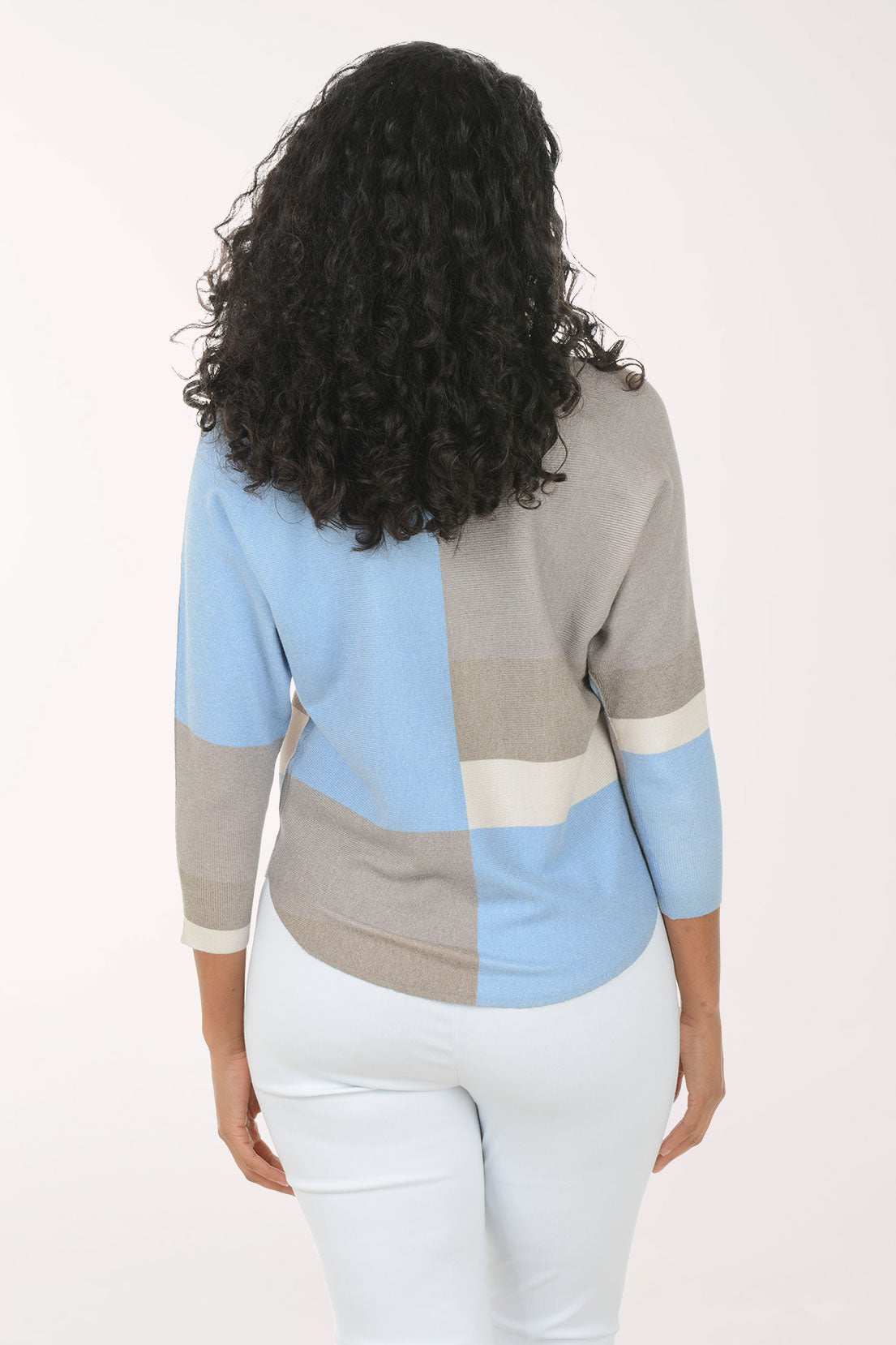 Woman wearing a color-blocked sweater with blue, gray, and beige sections on a white background.