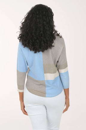 Woman wearing a color-blocked sweater with blue, gray, and beige sections on a white background.