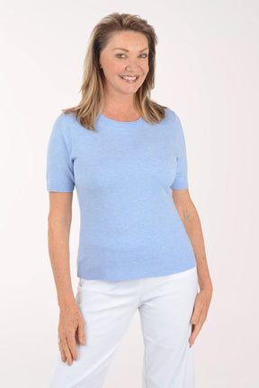 Woman wearing a light blue t-shirt and white pants on a white background