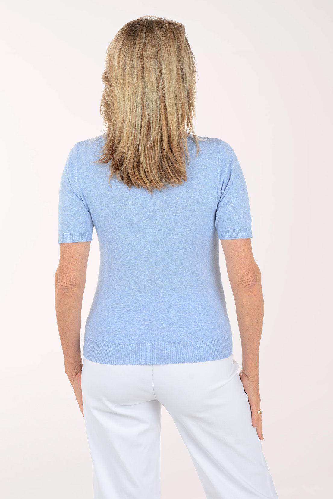 Woman wearing a light blue t-shirt and white pants on a white background