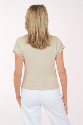 Woman wearing a beige top and white pants on a white background