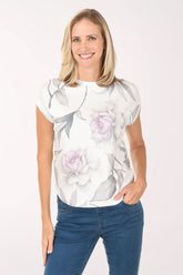 Woman wearing a white floral blouse with blue jeans on a white background