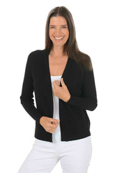 Woman wearing a long sleeve black cardigan sweater over a white top on a white background.