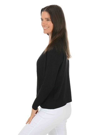 Woman wearing a long sleeve black cardigan sweater over a white top on a white background. Side shot.