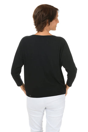 Woman wearing a black sweater with colorful flower patterns on a white background. Back shot.