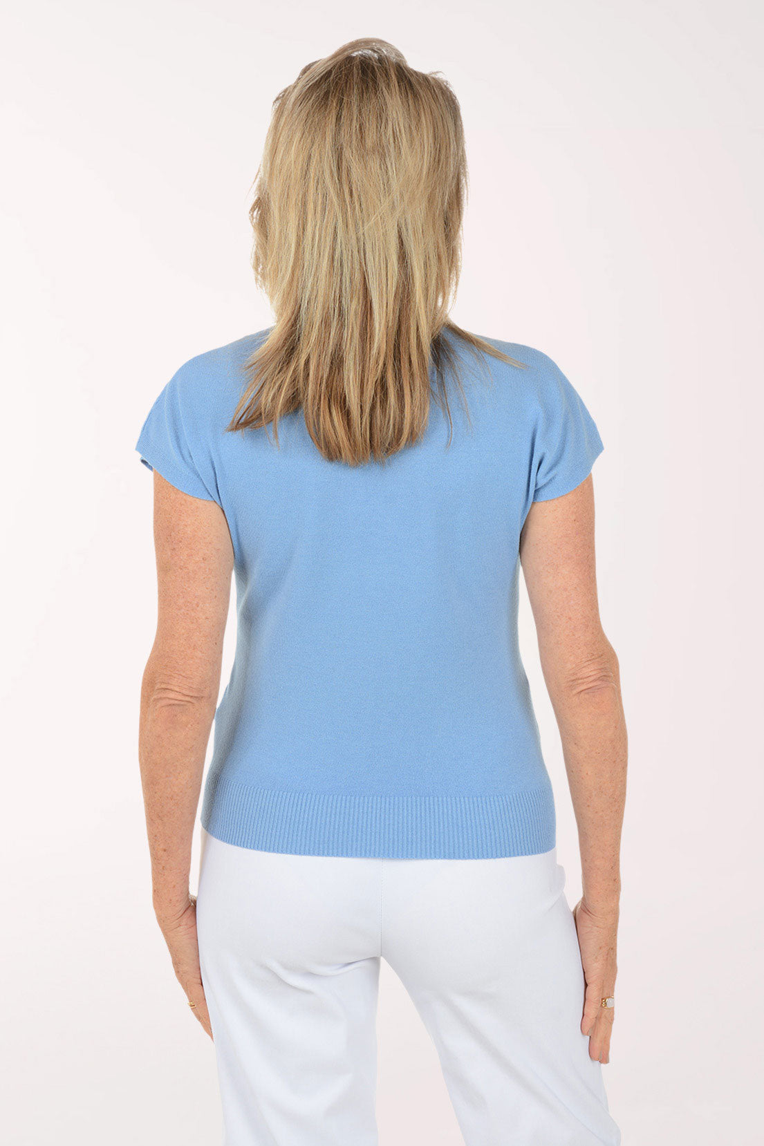 Woman wearing a light blue shirt and white pants on a white background