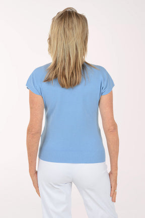 Woman wearing a light blue shirt and white pants on a white background