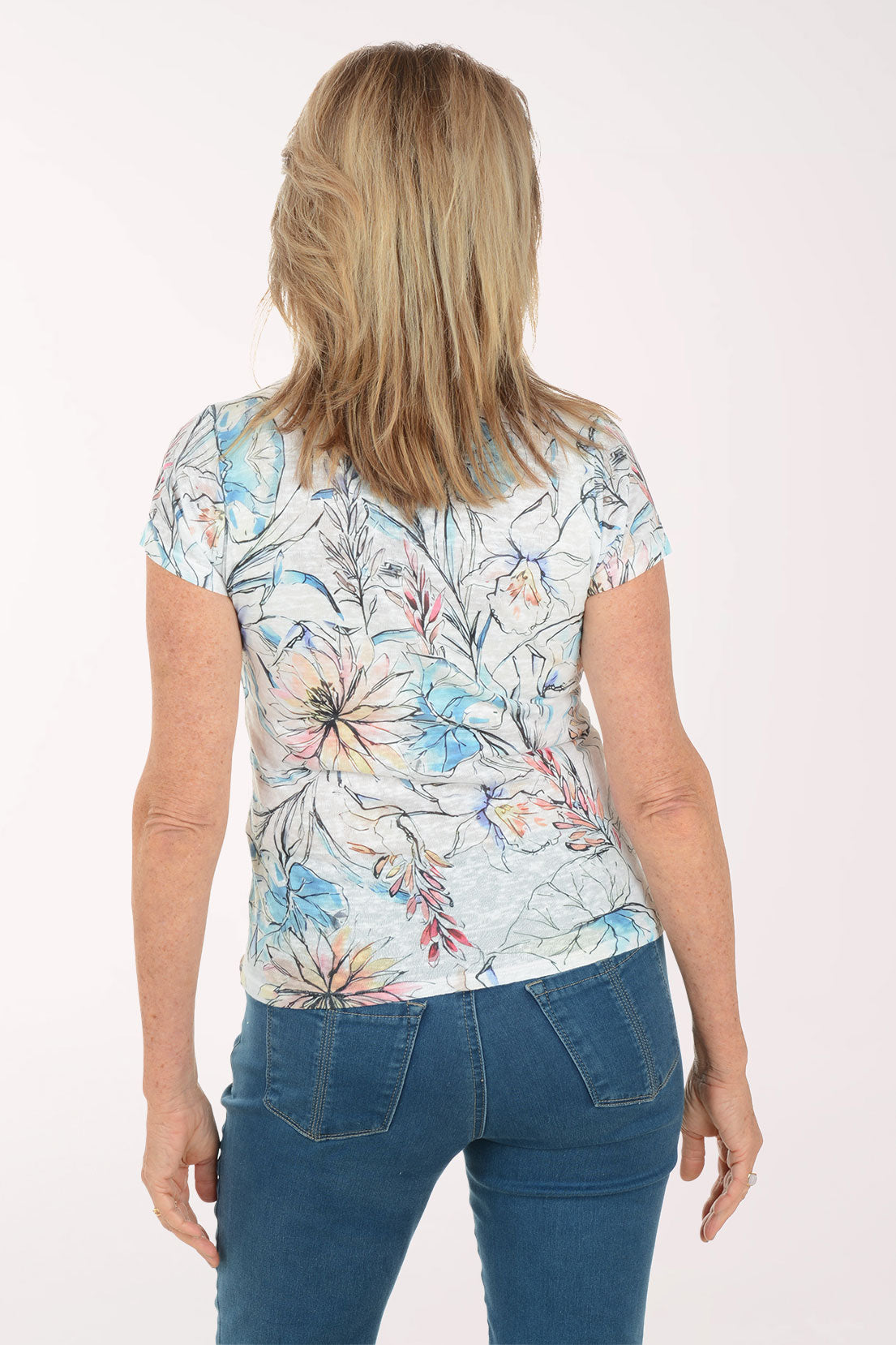 Woman wearing a floral top and blue jeans on a white background