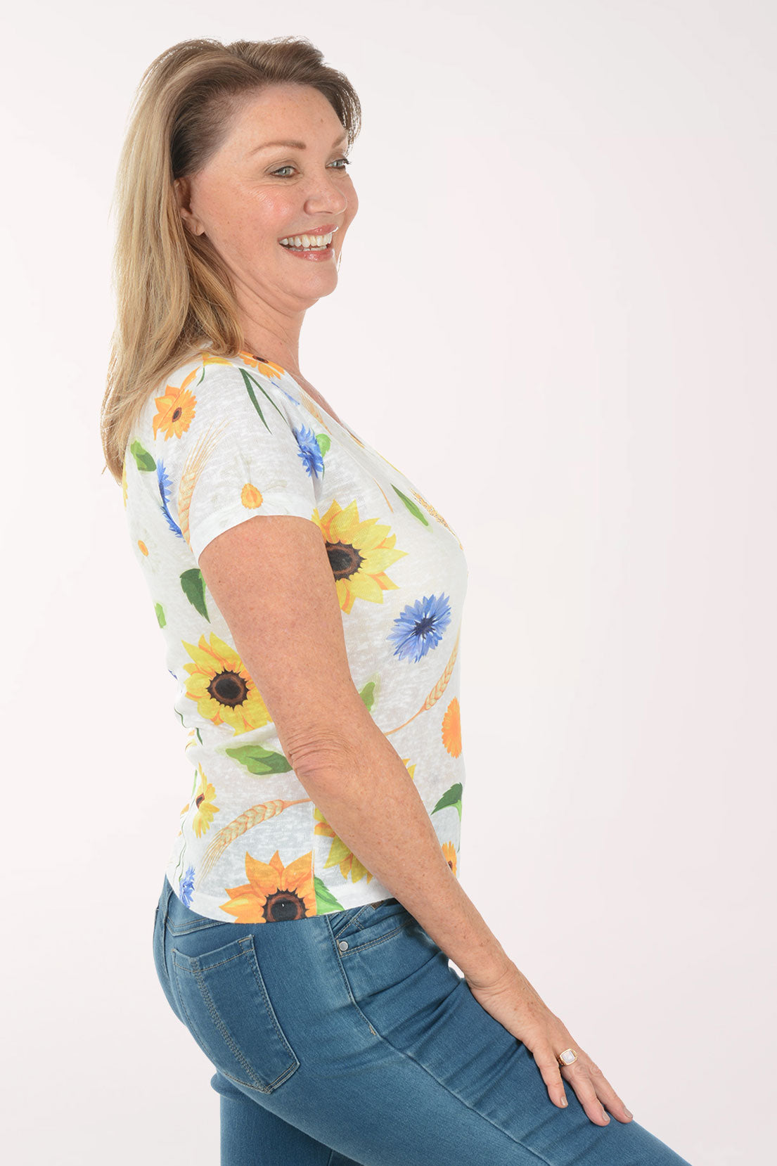 Woman wearing a floral-patterned shirt with blue jeans on a white background