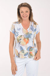 Woman wearing a short sleeve top with floral design on a white background