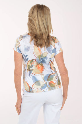 Woman wearing a short sleeve top with floral design on a white background