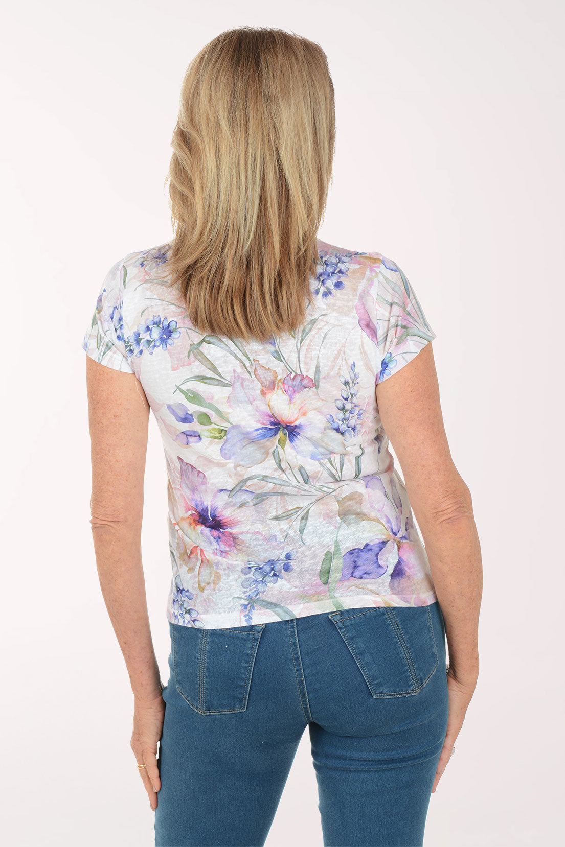 Woman wearing a floral-patterned shirt and blue jeans on a white background