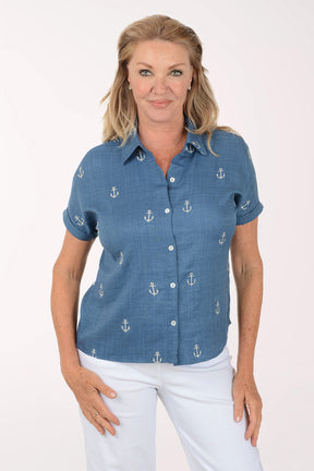 Woman wearing a blue shirt with anchor patterns on a white background