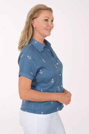 Woman wearing a blue shirt with anchor patterns on a white background