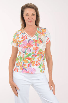 Woman wearing a colorful floral top and light blue pants on a white background