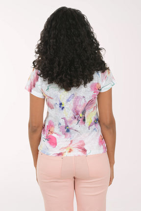 Woman wearing a floral top and pink pants on a white background