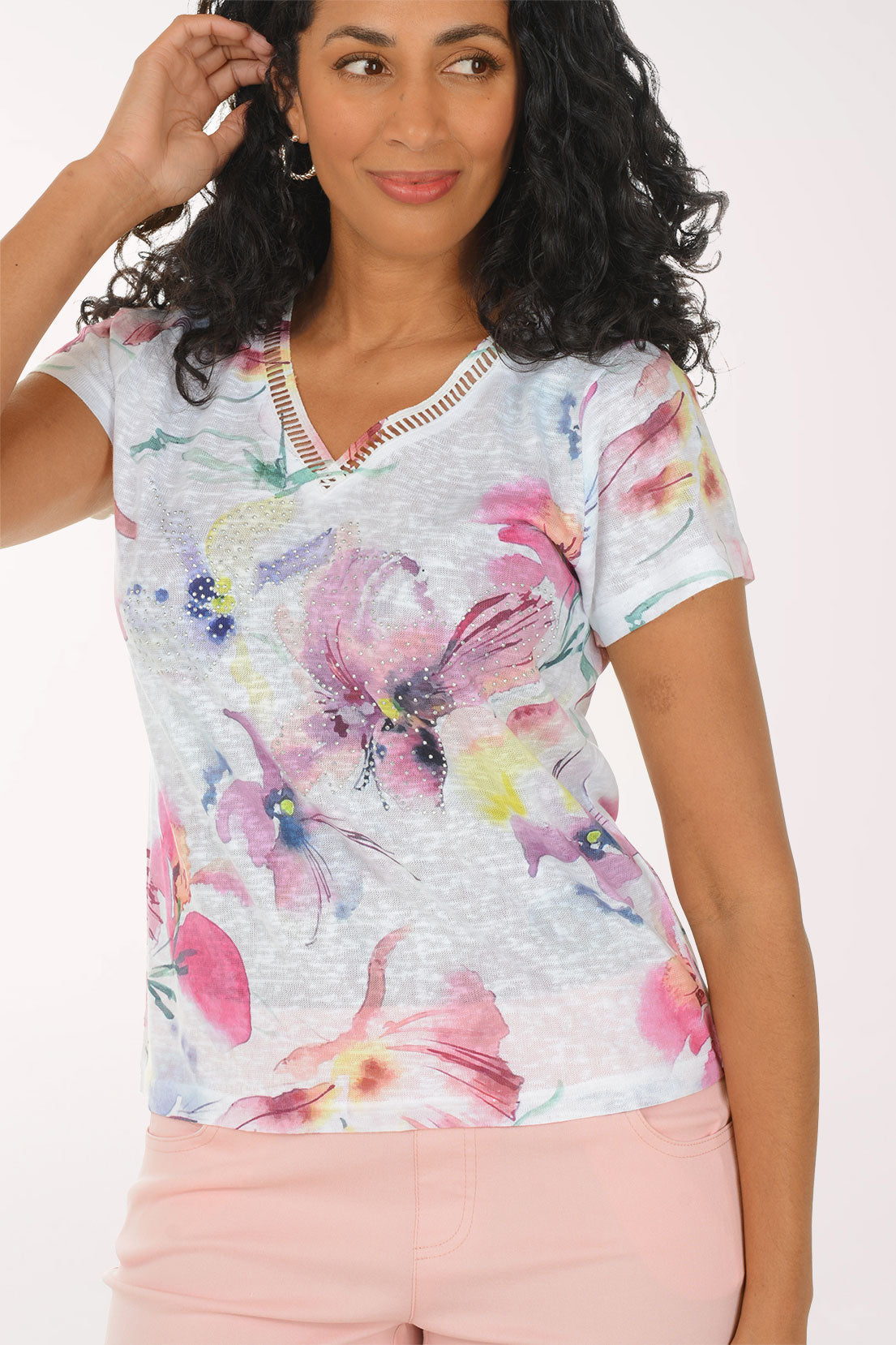 Woman wearing a floral top and pink pants on a white background