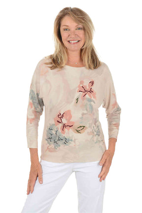 Woman wearing a 3/4 sleeve floral long-sleeve sweater with embroidered accents on a white background. Side shot.