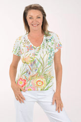 Woman wearing a floral blouse and white pants on a white background