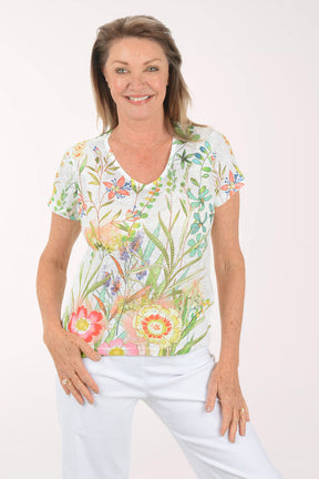 Woman wearing a floral blouse and white pants on a white background