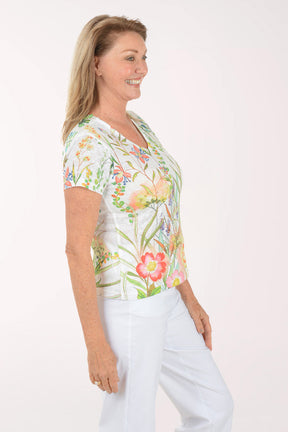 Woman wearing a floral blouse and white pants on a white background