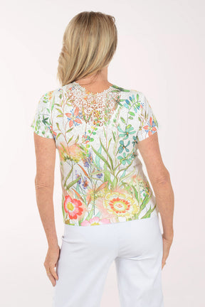 Woman wearing a floral blouse and white pants on a white background