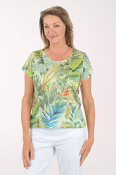 Woman wearing a tropical leaf patterned shirt against a white background
