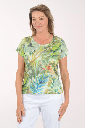 Woman wearing a tropical leaf patterned shirt against a white background