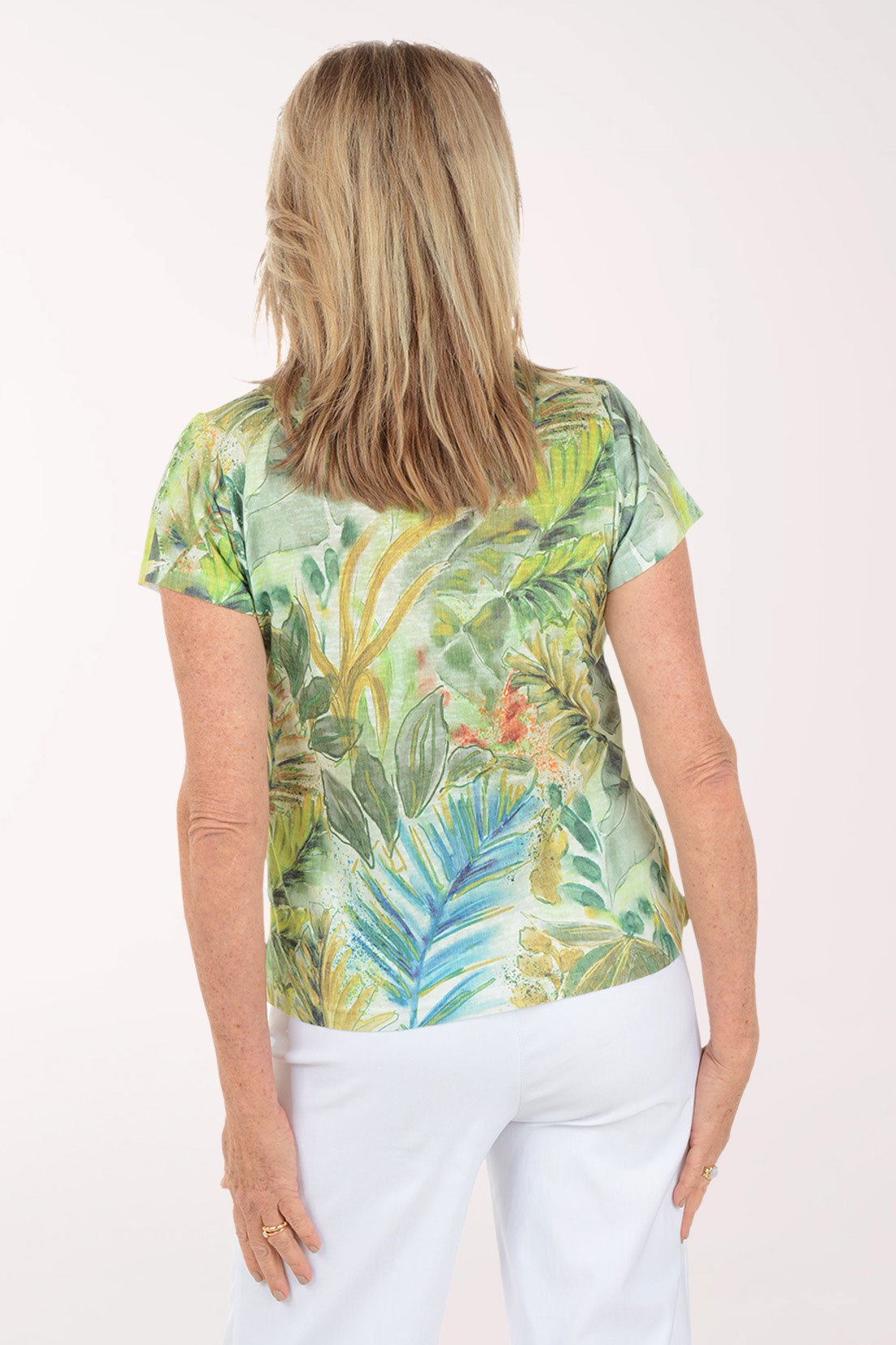 Woman wearing a tropical leaf patterned shirt against a white background