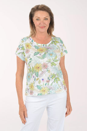 Woman wearing a floral print top and white pants on a white background